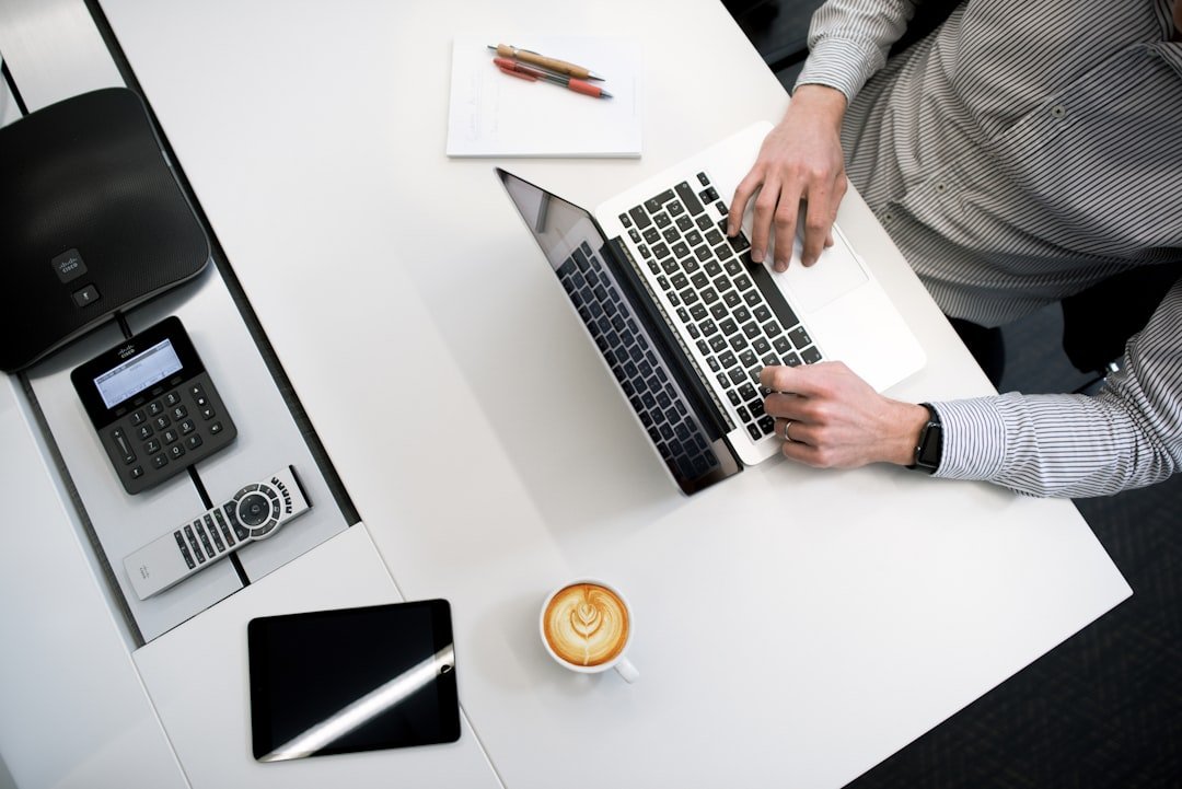 Person using a laptop on a white desk representing office productivity software